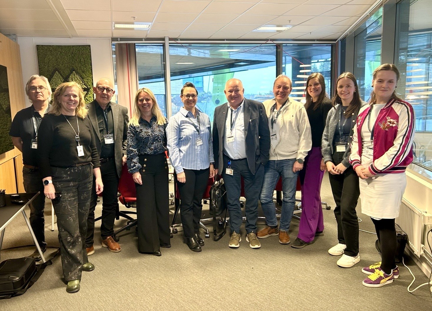 A person wearing a virtual reality headset stands in front of multiple screens, engaged in a digital experience.