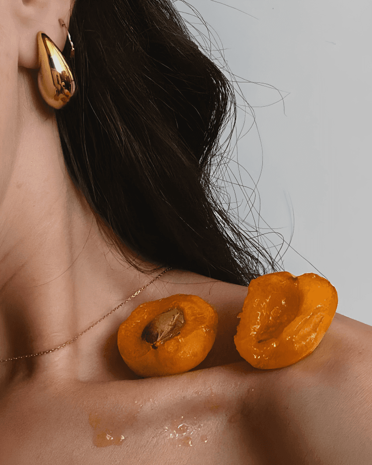 Woman with peaches resting on her shoulder