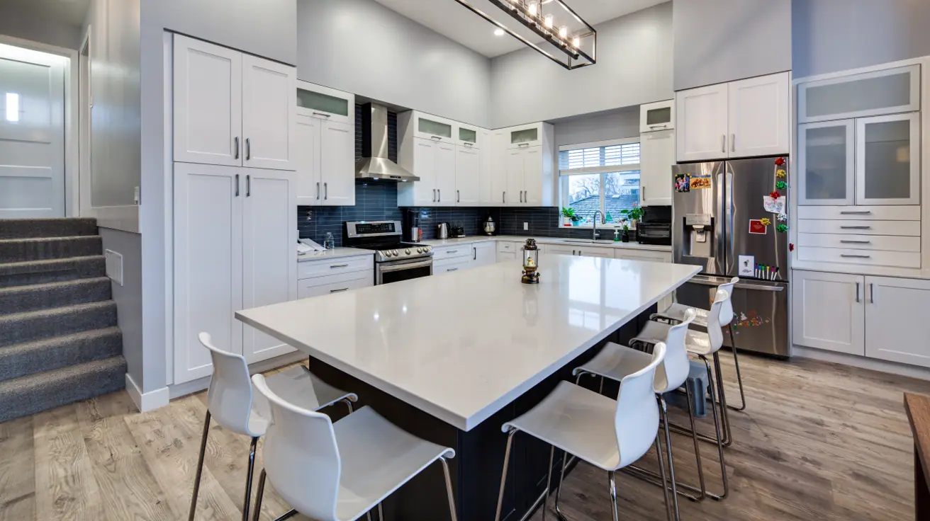 Contemporary kitchen design with crisp white shaker-style cabinets, sleek black subway tile backsplash, professional-grade stainless steel appliances, large functional island with bar seating, and integrated office workspace