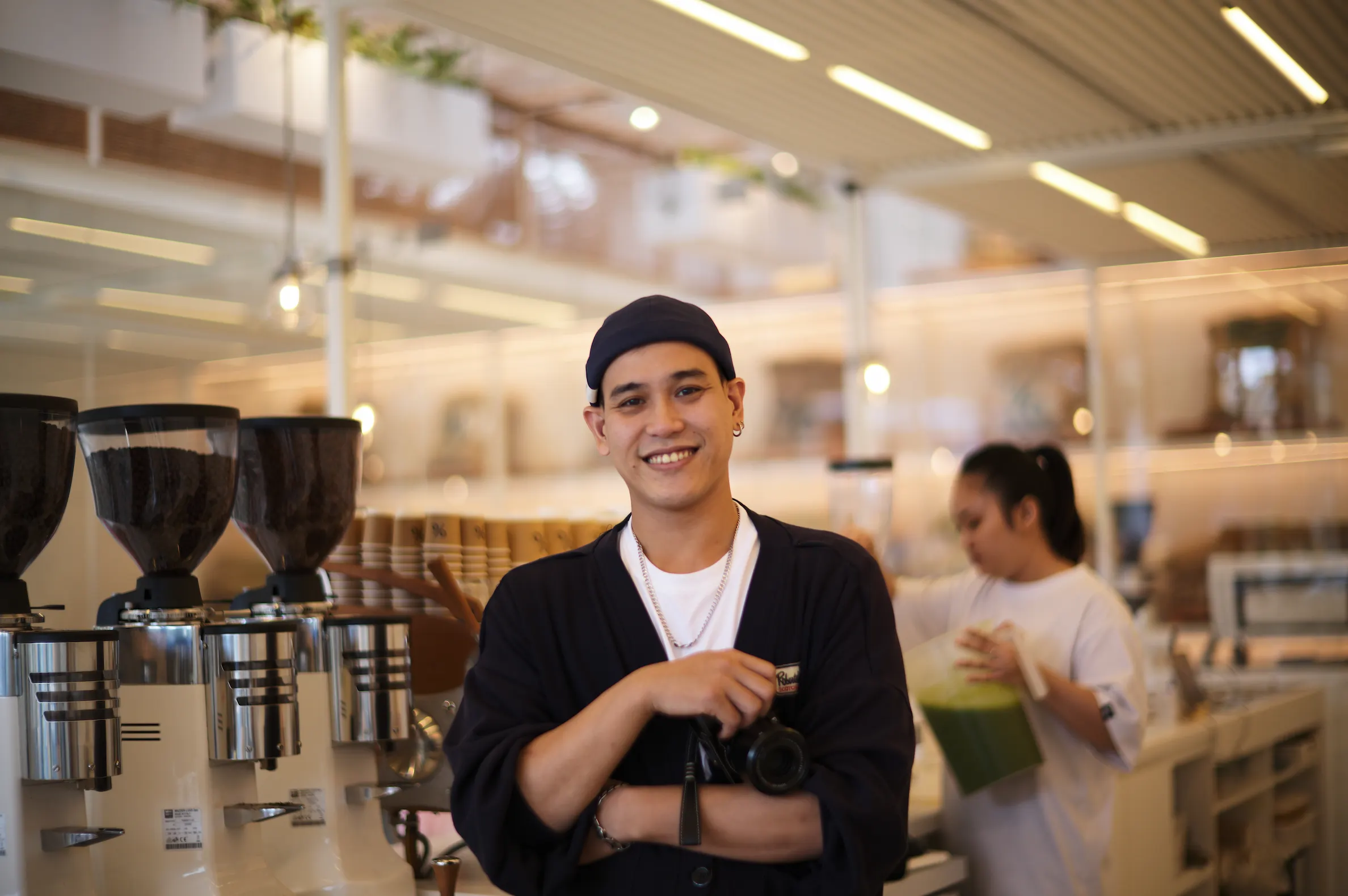 Hoàng Lâm, brand-led web and Framer designer, smiling in a specialty coffee shop in Saigon