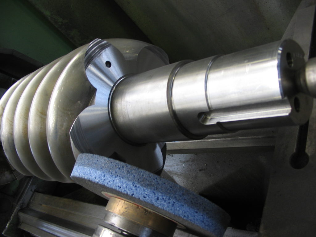 Schroefcompressor rotor op slijpmachine tijdens nabewerking lagerzitting, precisiewerk door Plasma Service