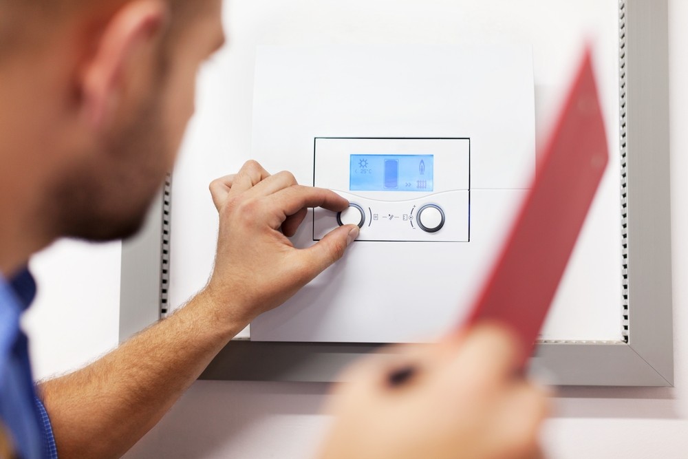 An engineer adjusting the settings on an electric boiler