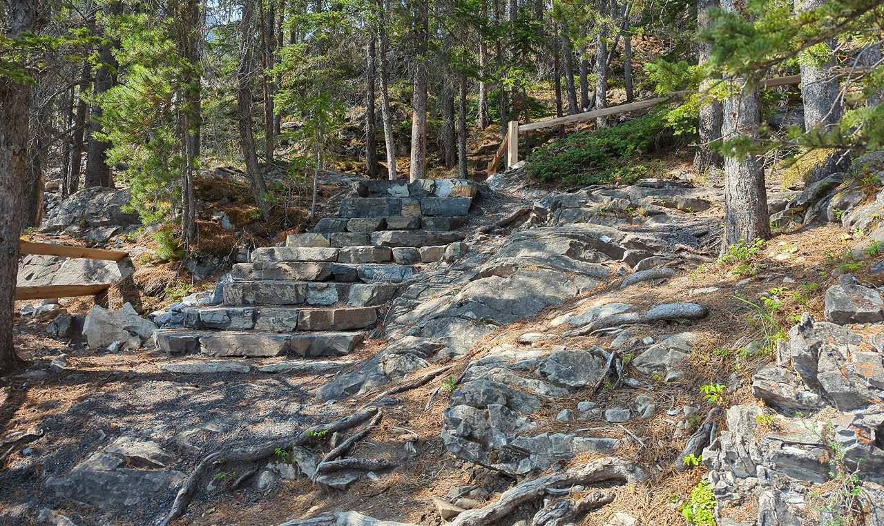 Stone staircase with wooden railing on improved Grassi Lakes trail managing steep terrain