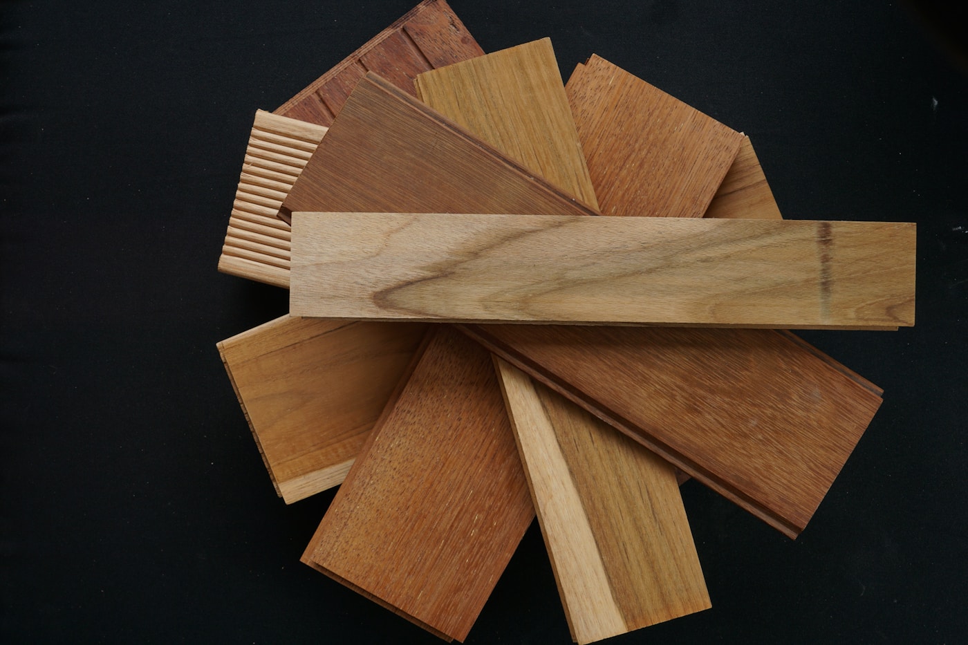 Warm wood offcuts arranged as finish samples on a dark work surface