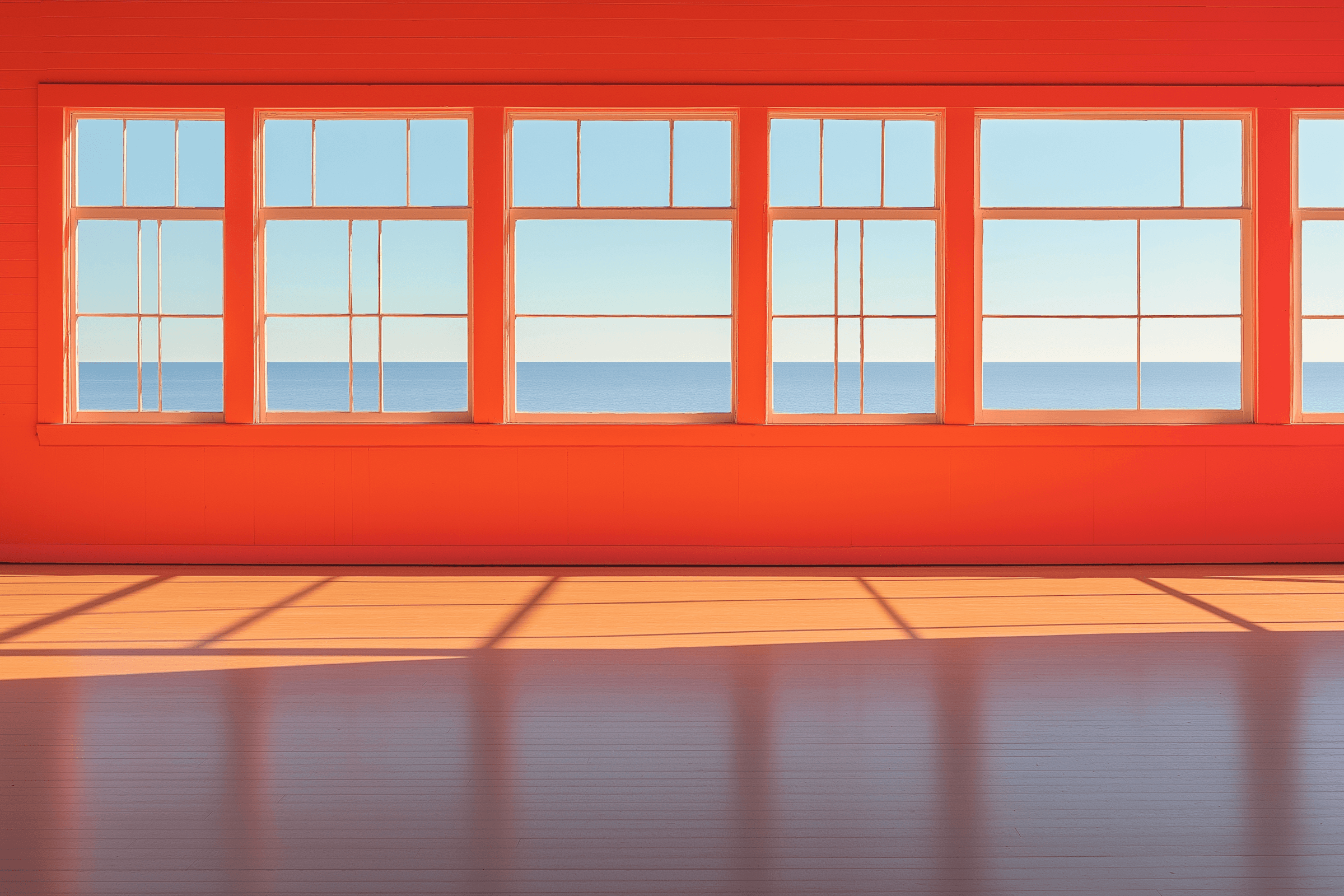 Orange room with windows looking out to the ocean.