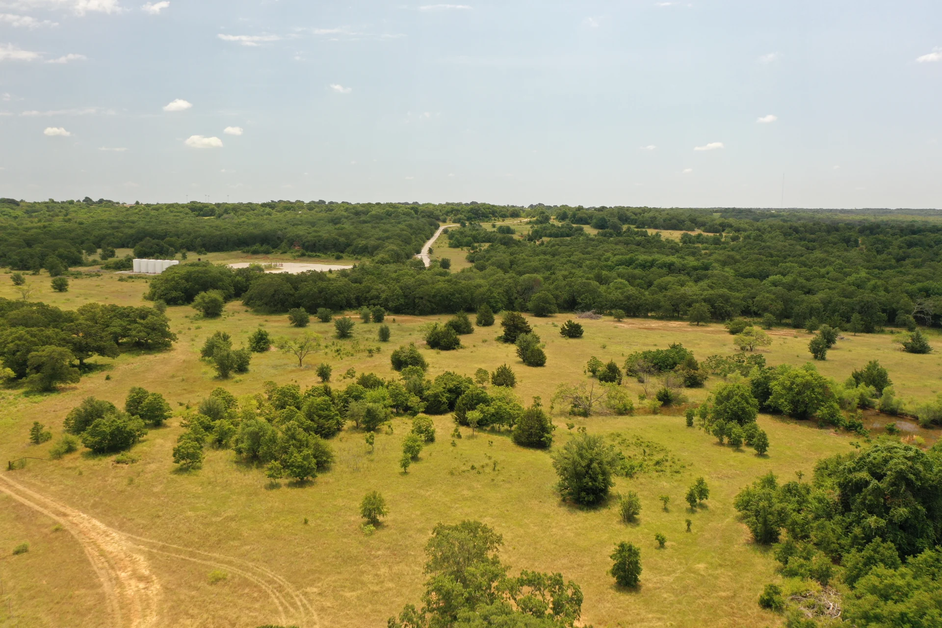 Open Texas acreage with trees and an established road corridor
