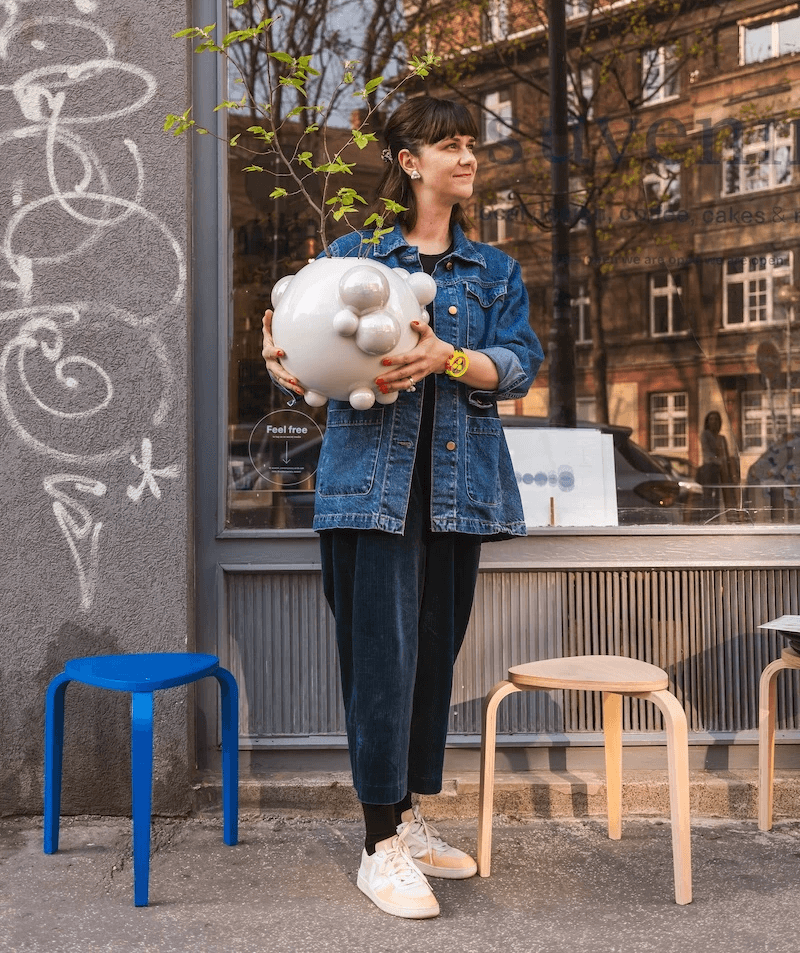 Nina A. Šošková s porcelánovou vázou z kolekcie BUBBLES pred výkladom contemporary_suvenir shop & café