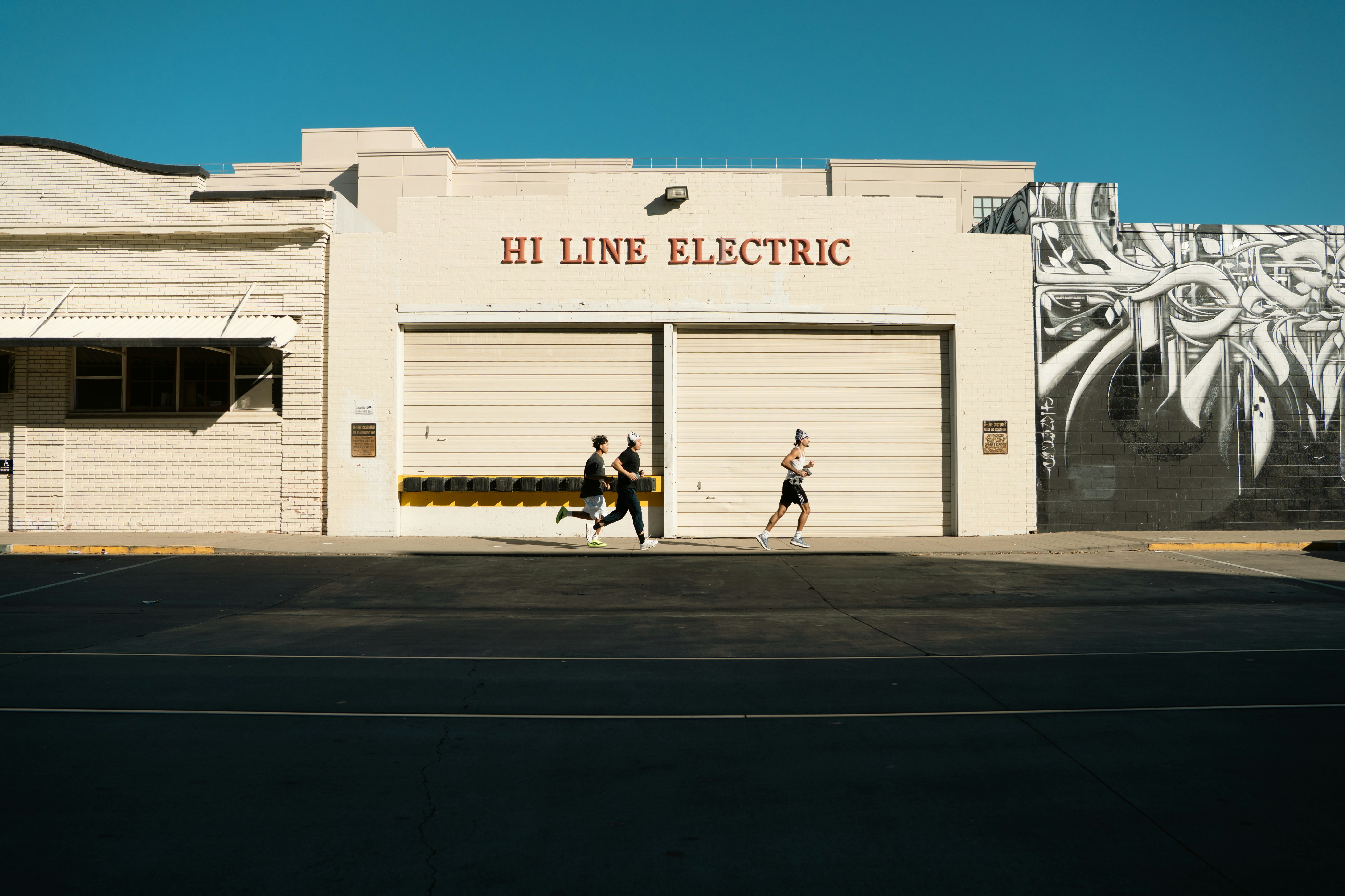 Three people running in front of a building.