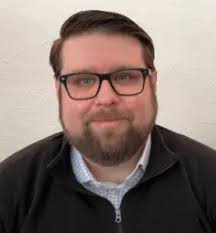 Man in glasses and beard wearing a zipped jacket