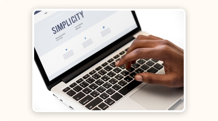  A hand on a laptop keyboard with the word 'SIMPLICITY' on screen, symbolizing a clean and intuitive user interface.