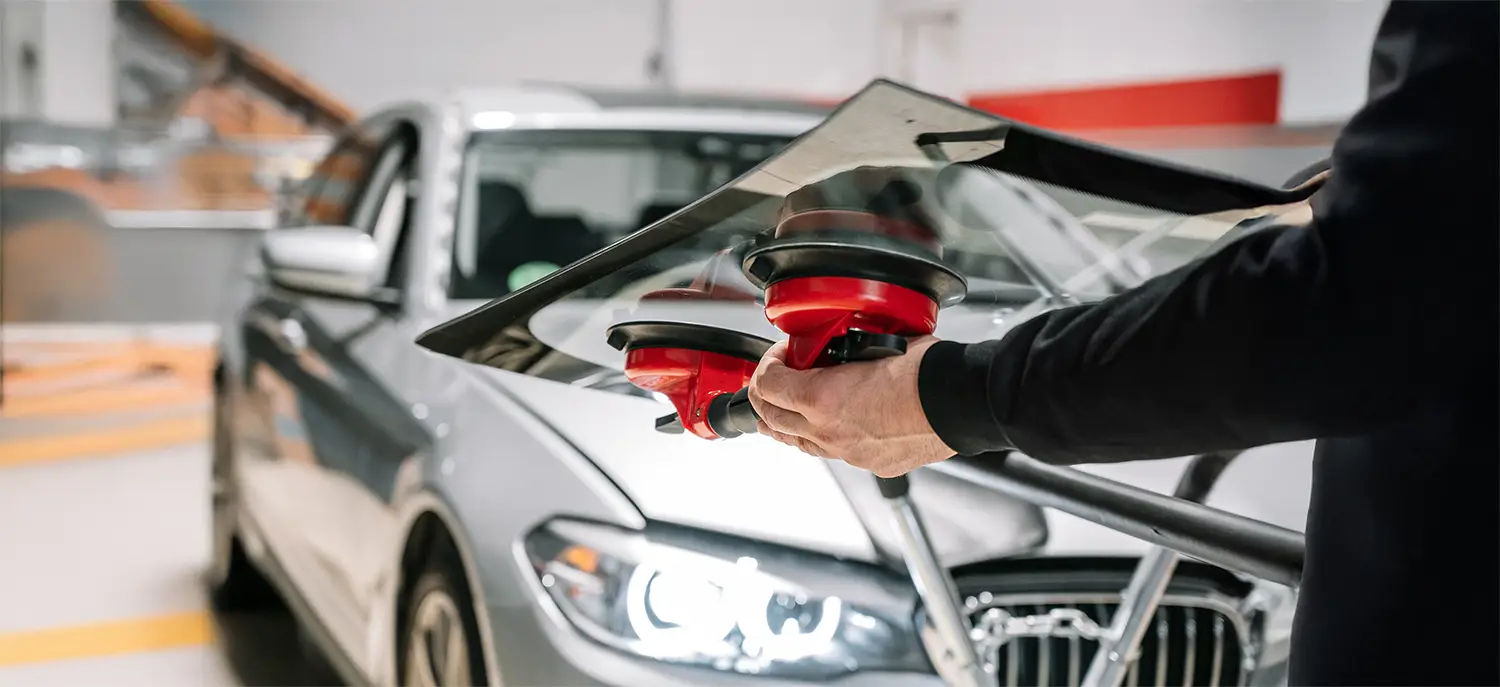 Technician installing automotive glass using professional suction tools for secure windshield replacement.