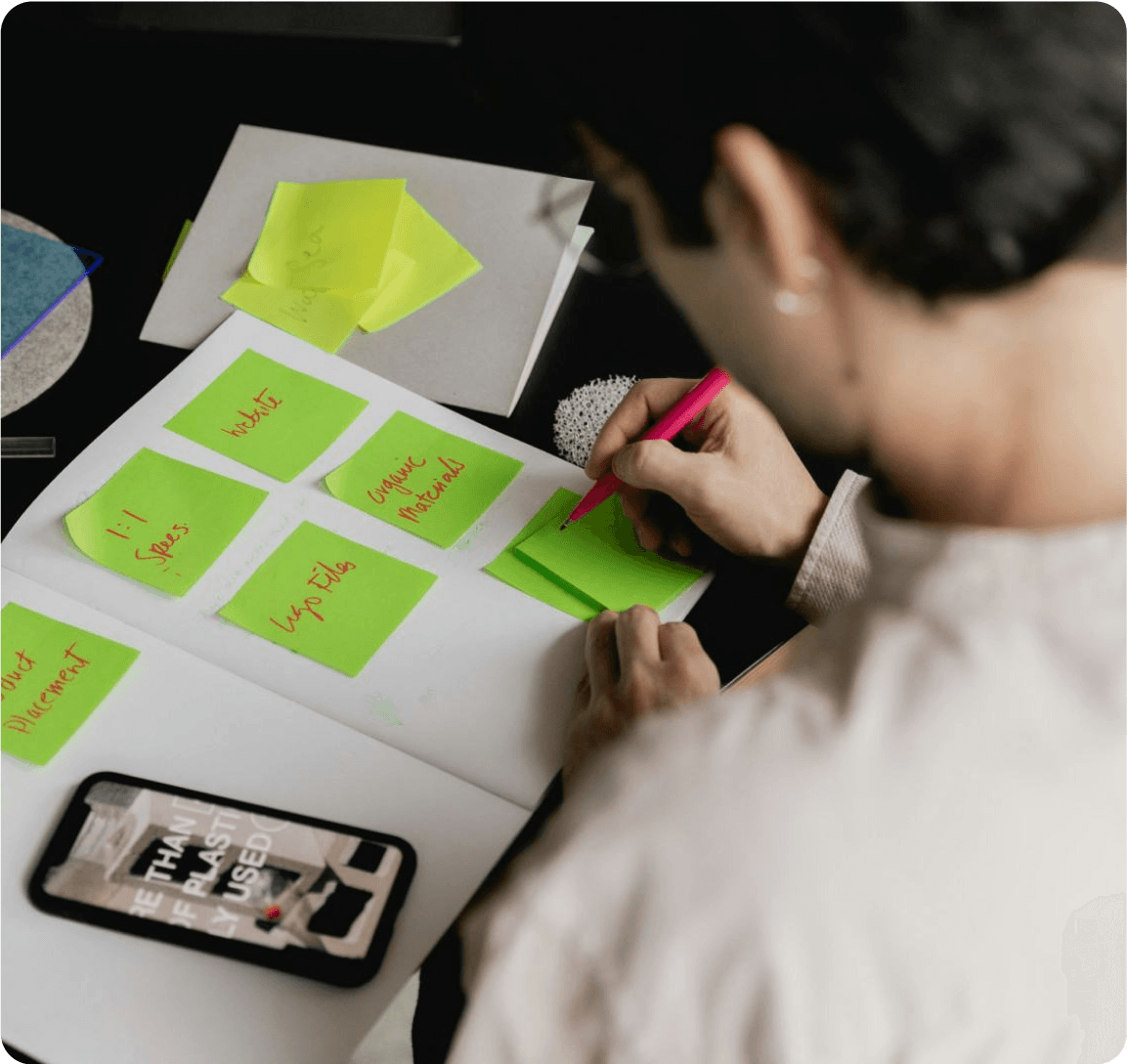 A person focused on a project, surrounded by colorful sticky notes on a desk, illustrating organization and creativity.