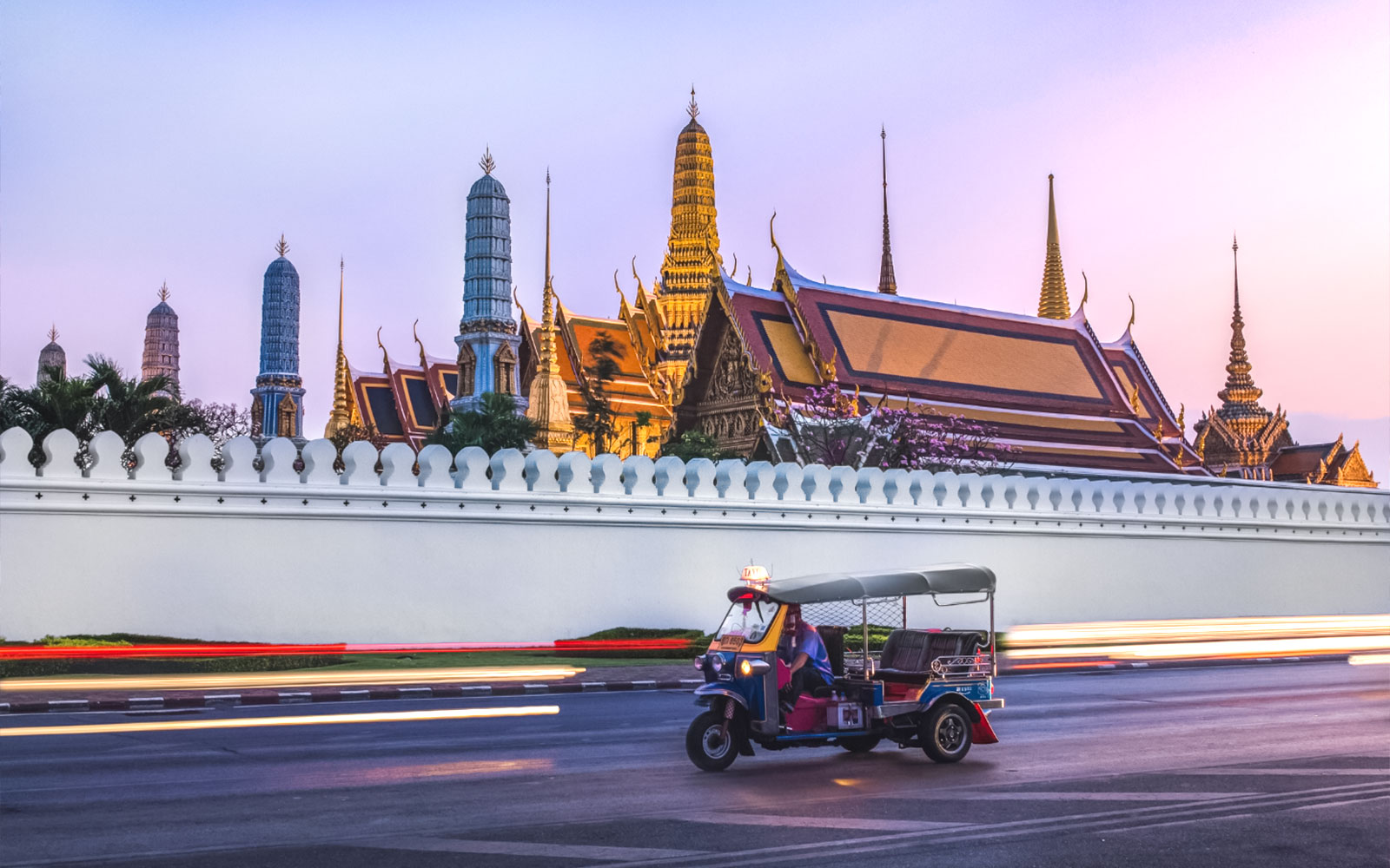 日落时分，嘟嘟车驶过曼谷的大皇宫。