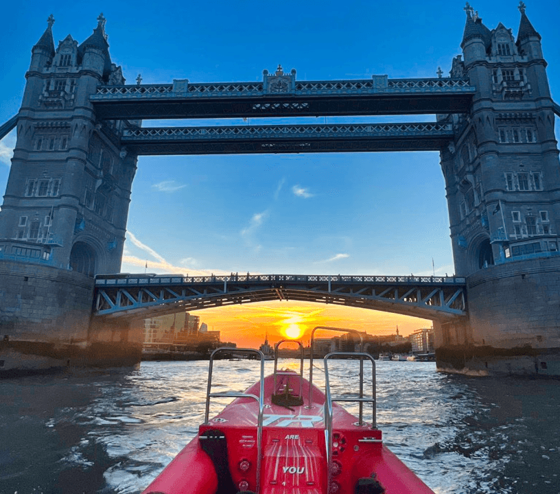 Thames Rockets Nights Speedboat Experience: The tip of the Thames Rocket RIB speeds points to the setting sun under Tower Bridge