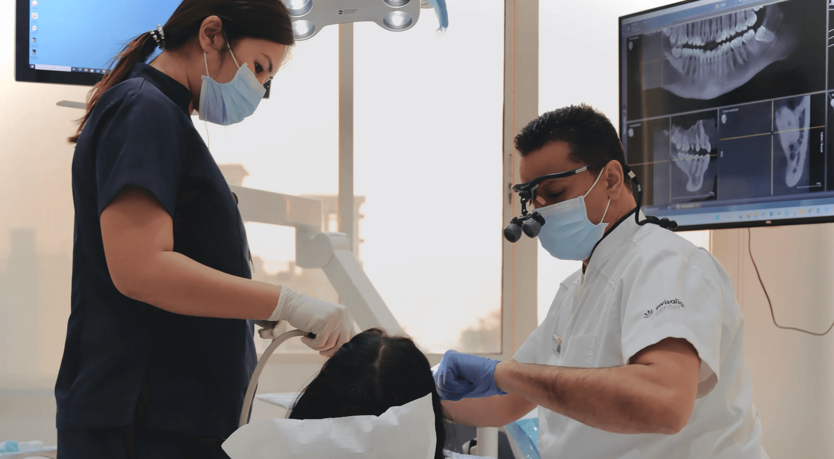 A dentist and his assistant are performing a regular check-up and cleaning for a patient to prevent her from having sensitive teeth by Invisalign Center