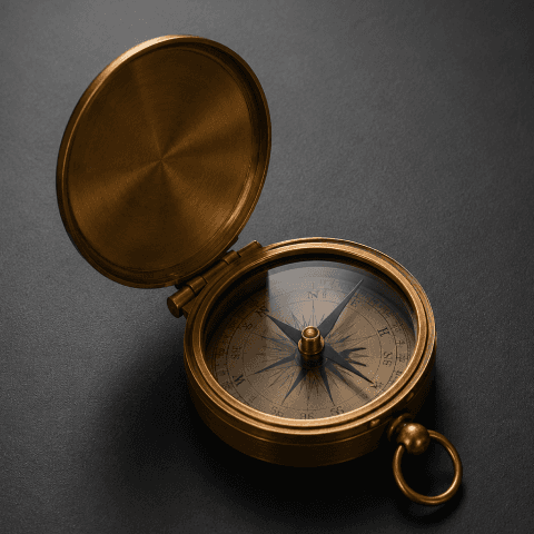 A rose-gold compass on a dark matte office table.