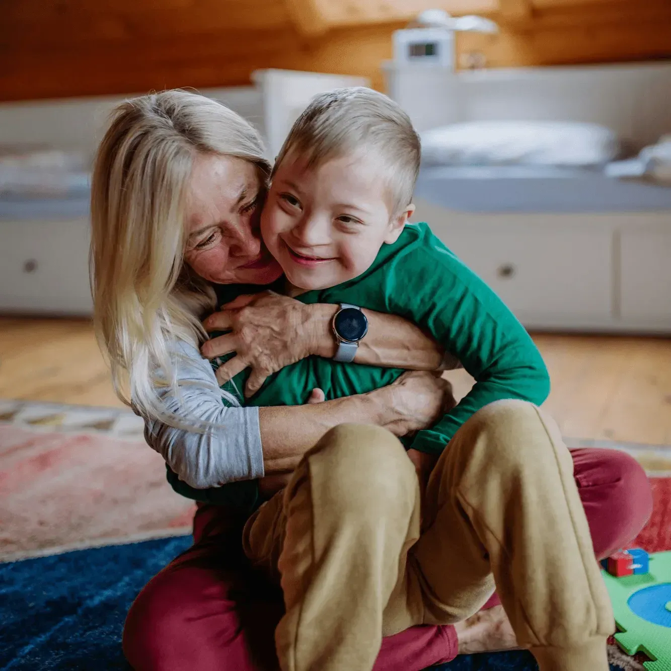 Woman hugging a smiling young boy indoors.