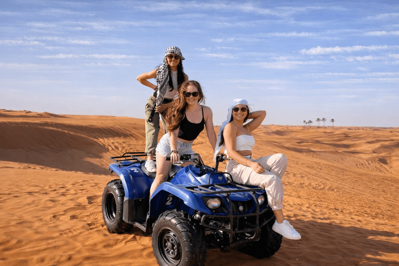 Three women enjoying a quad bike experience in the Dubai desert with Dune Quest Tours.