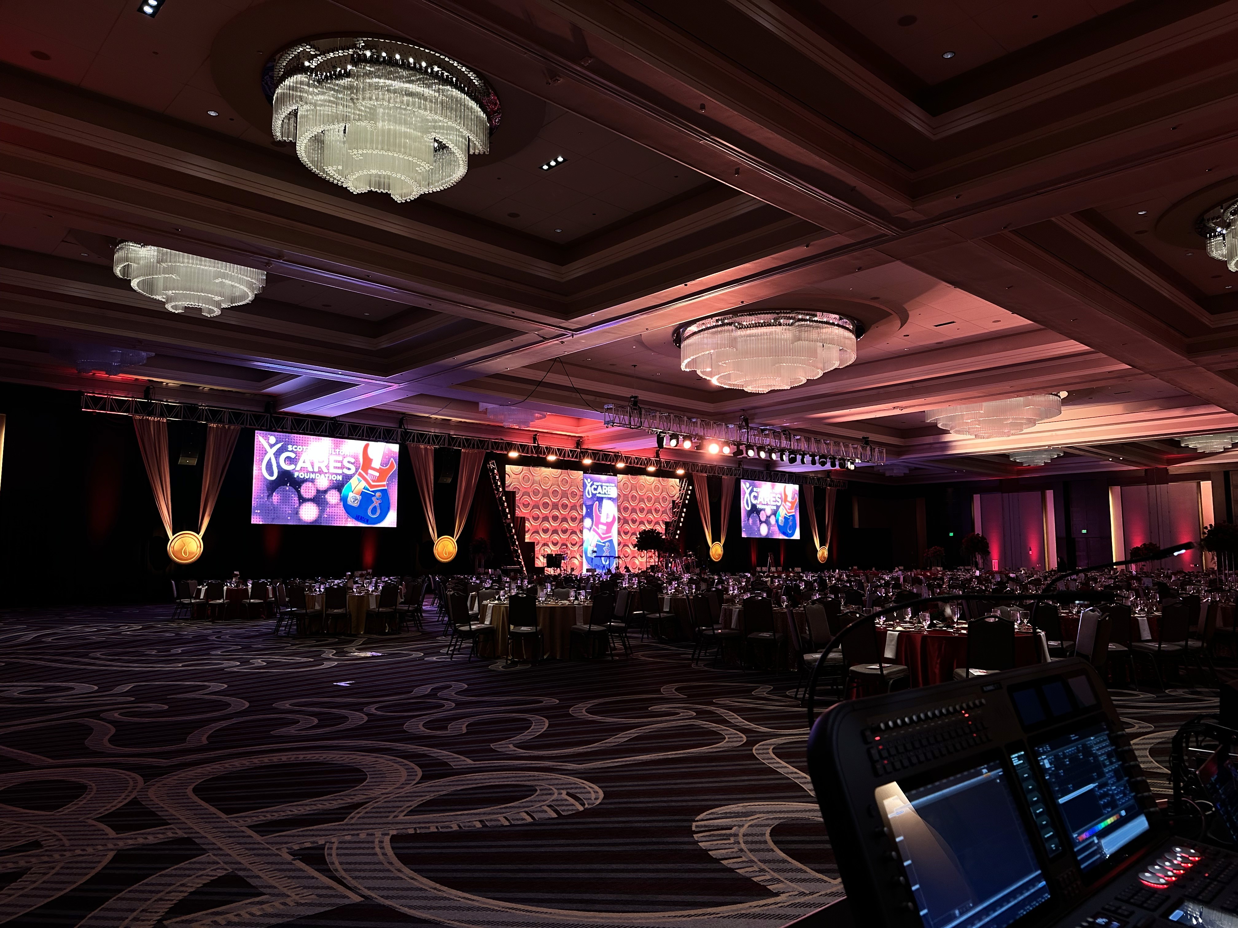 Corporate ballroom gala with ornate chandeliers and a stage with LED screens