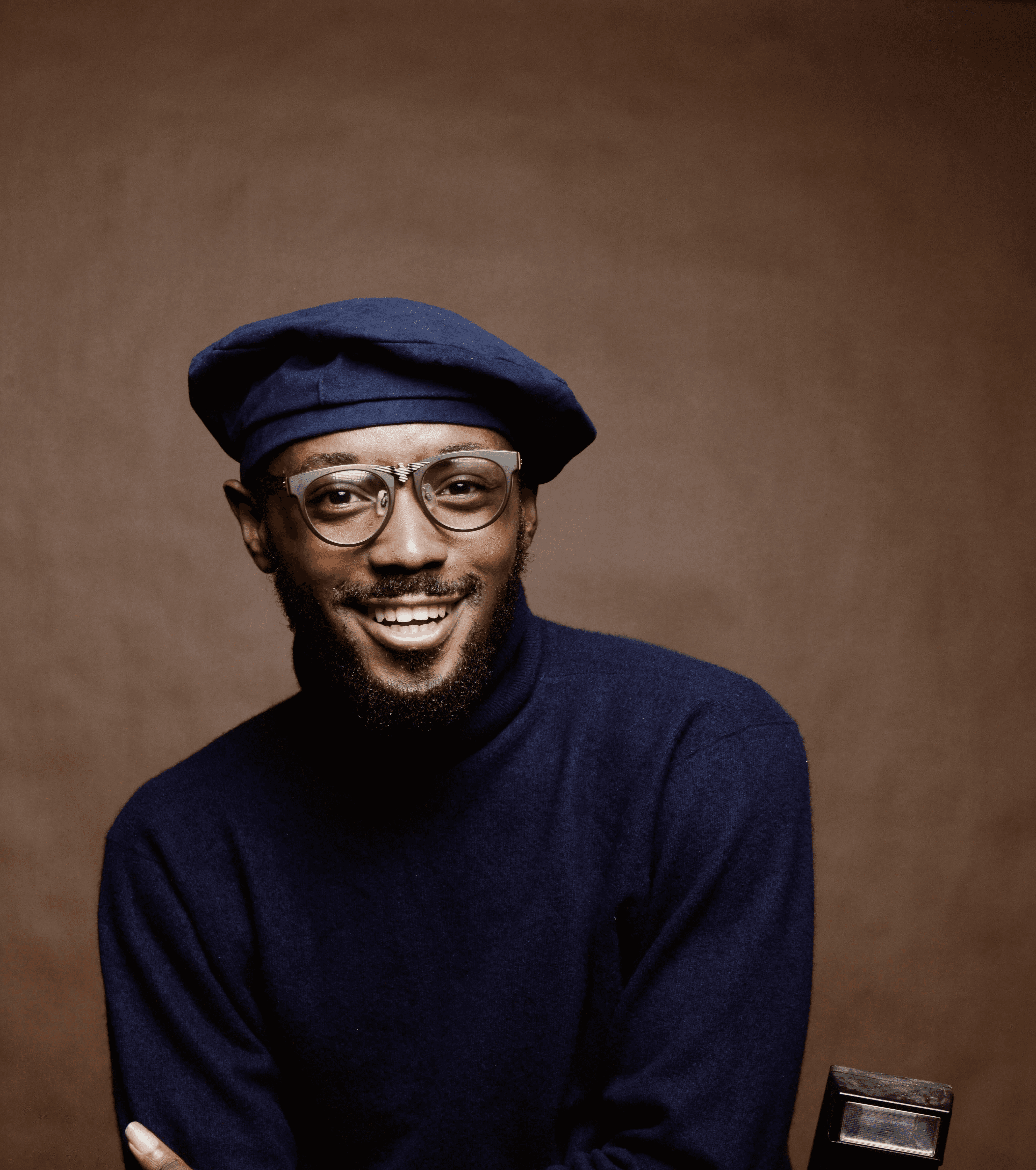 smiling man wearing black turtleneck shirt holding camrea