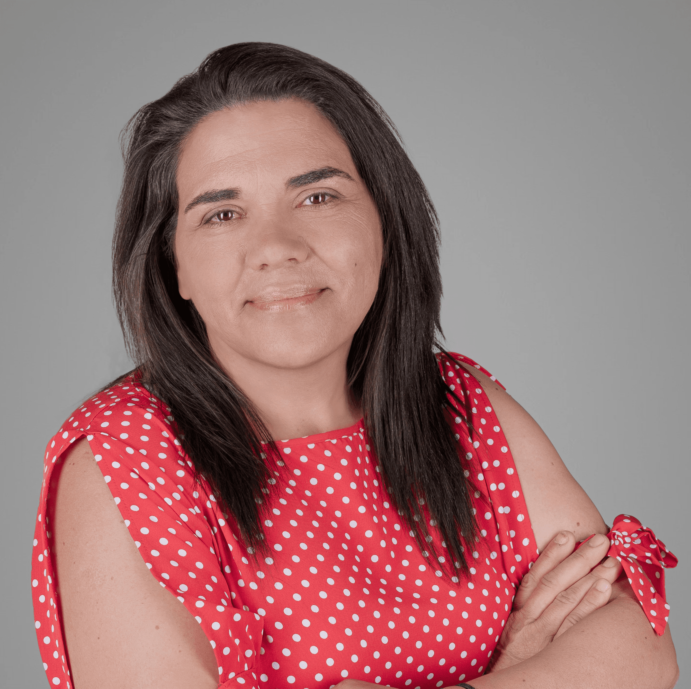 A wooden desk by a window, with sunlight illuminating a laptop, notebook, and a decorative vase.