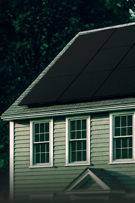 A smiling young man with crossed arms, wearing a plaid shirt and white t-shirt, poses against a dark background.