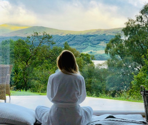 Photo of a woman facing away from camera overlooking a green, tranquil horizon