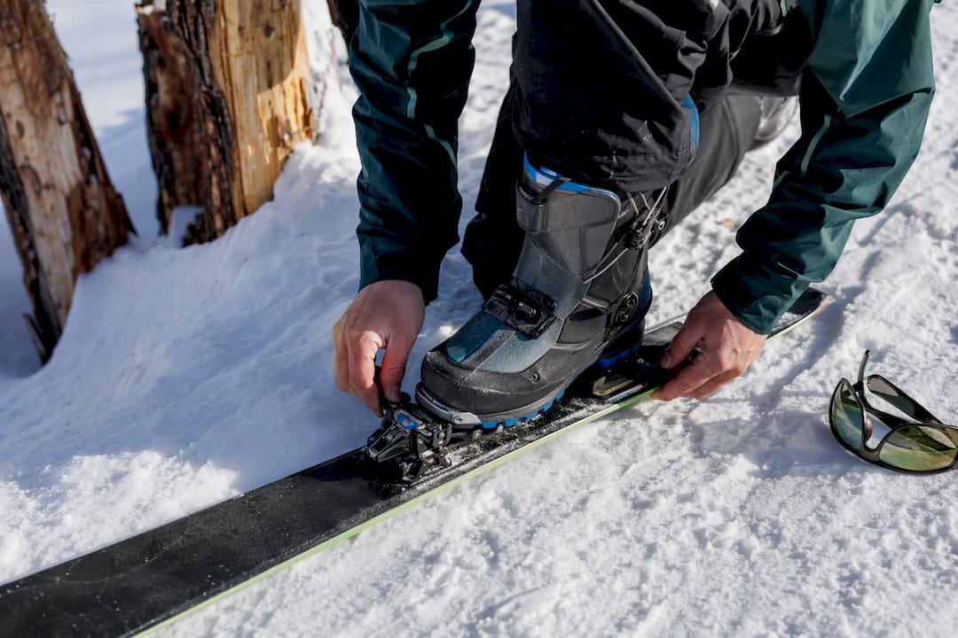 Skier fastening a touring ski binding in the snow