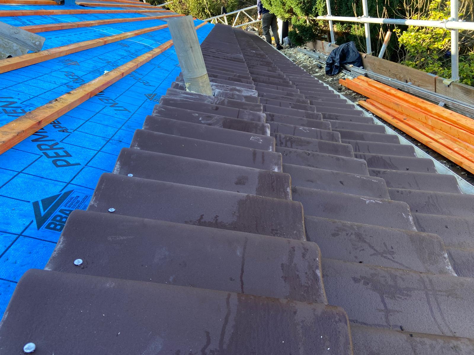 New roof tiles being laid over breathable membrane and treated battens