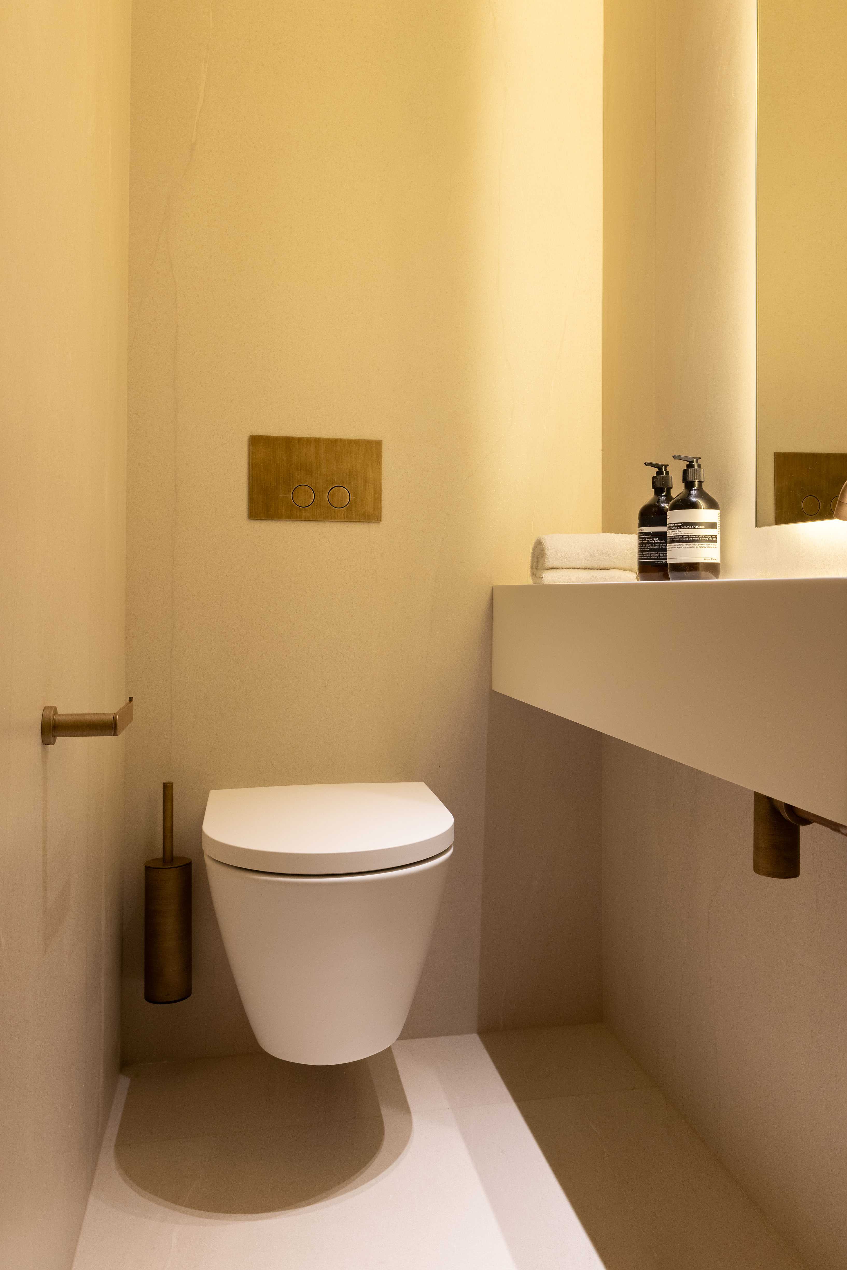 Toilettes suspendues avec éclairage tamisé, vasque, produits et porte-balai doré