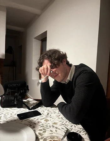 Jonas Parna resting his head on his hand at a table in a dim room
