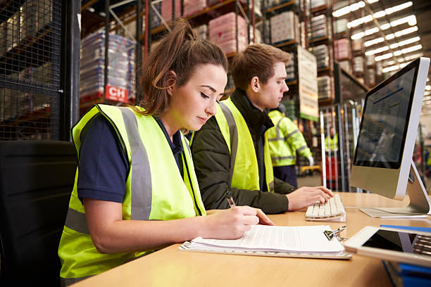 Image of two people wearing high vis working on some paperwork in a warehouse