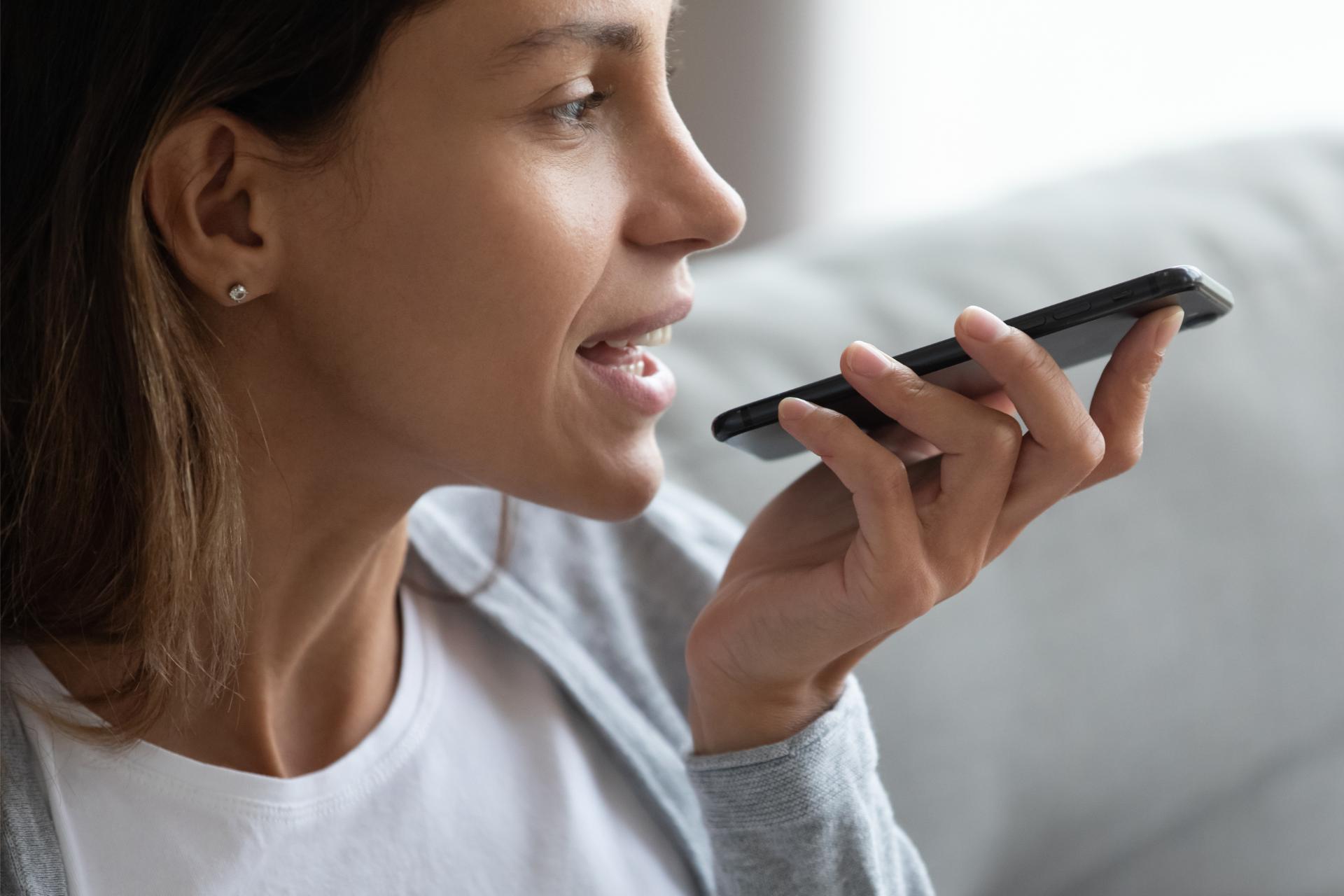 Young woman hold modern cellphone record voice message texting online