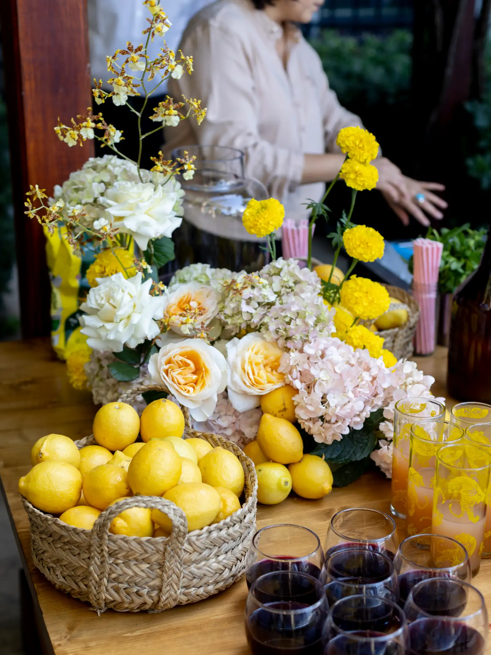 Mesa de cóctel con flores amarillas, limones y bebidas para evento diurno, inspirada en una estética vibrante y mediterránea.
