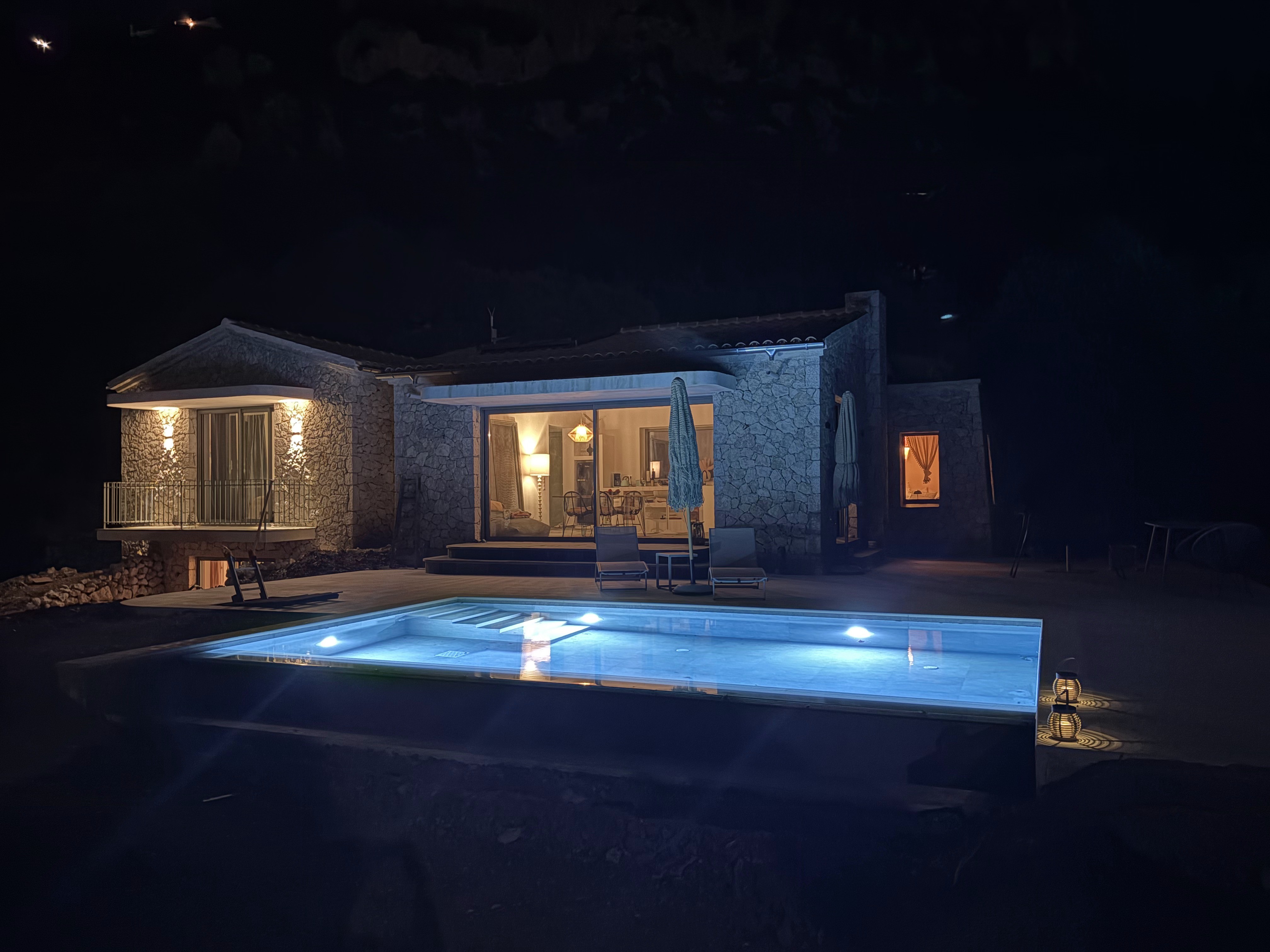 Night view of Loulis House with illuminated pool and terrace.