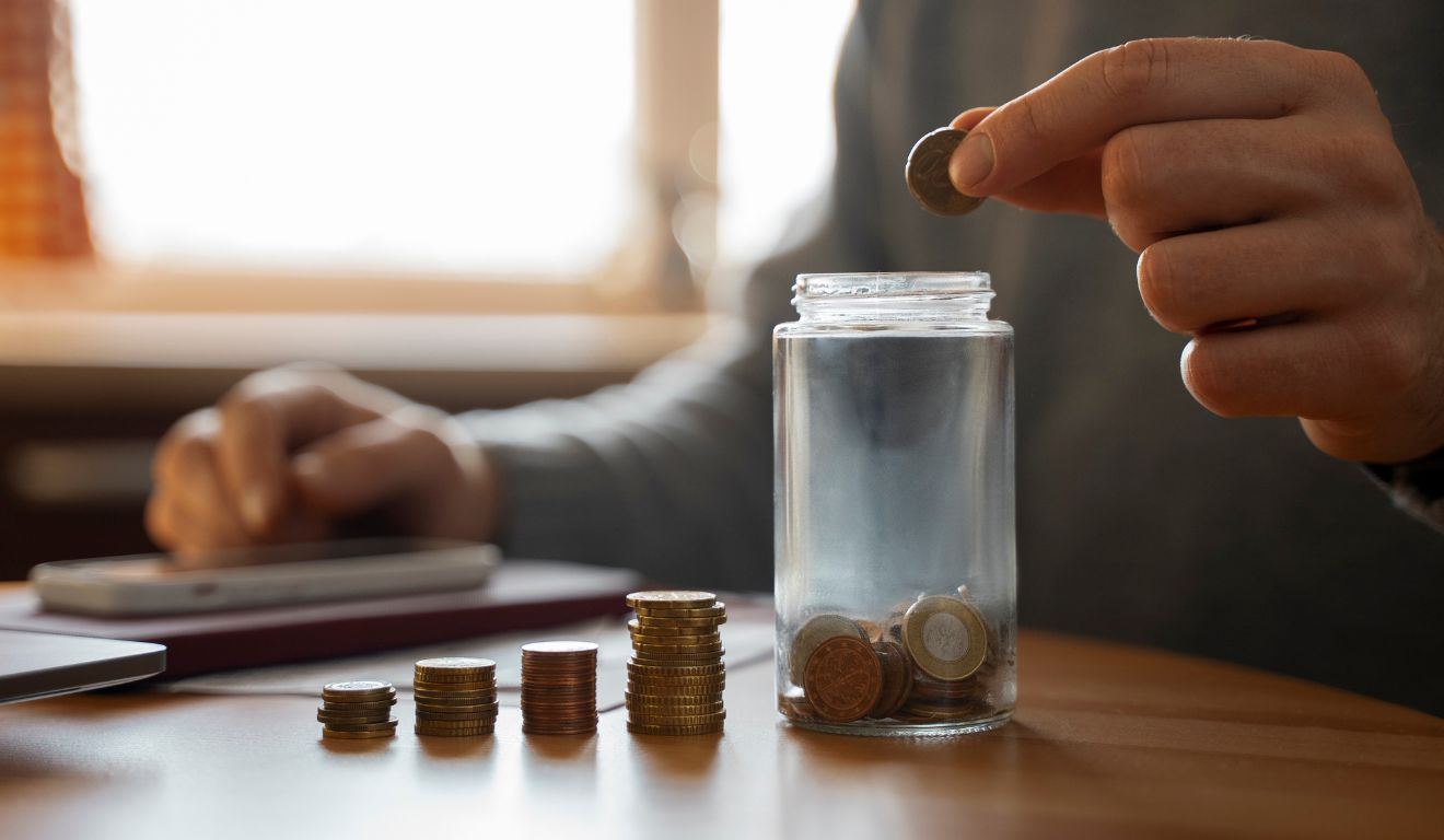 Homem reunindo moedas para guardar dinheiro em um pote de vidro