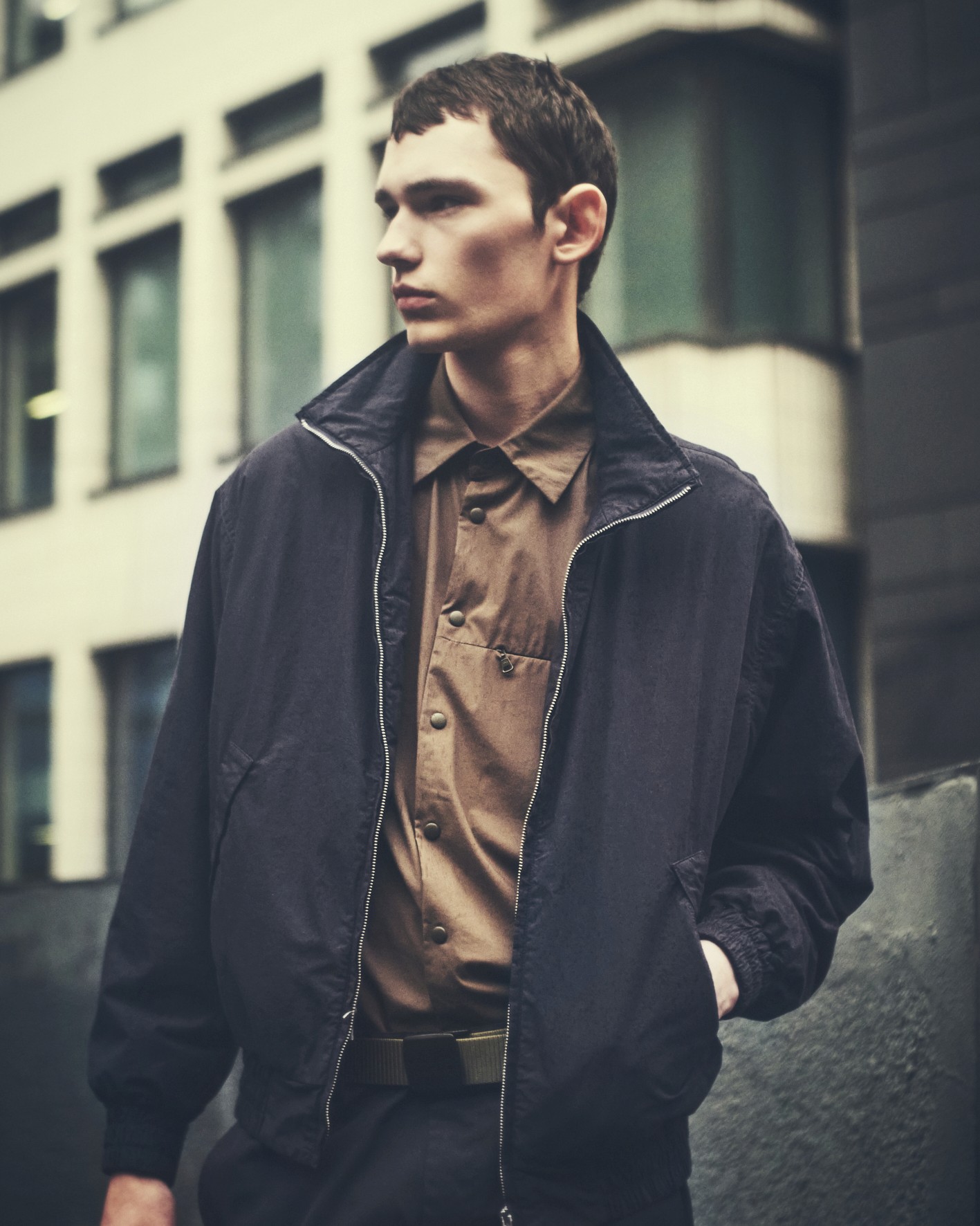 Un mannequin porte un blouson noir en nylon et une chemise beige de la marque Aspesi