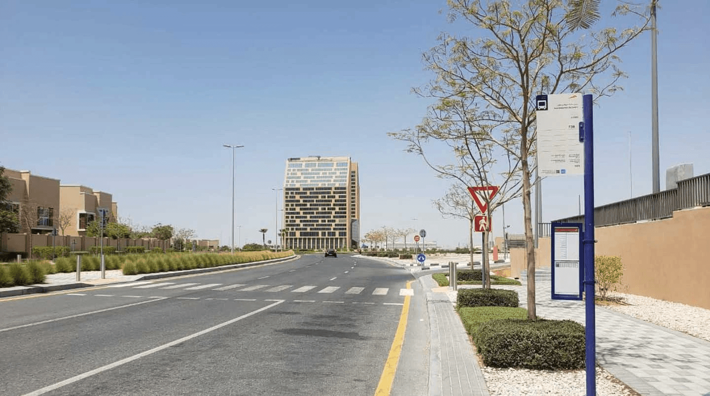 The building stands prominently on a busy street in Al Barsha South 2, with vehicles and people moving around it.