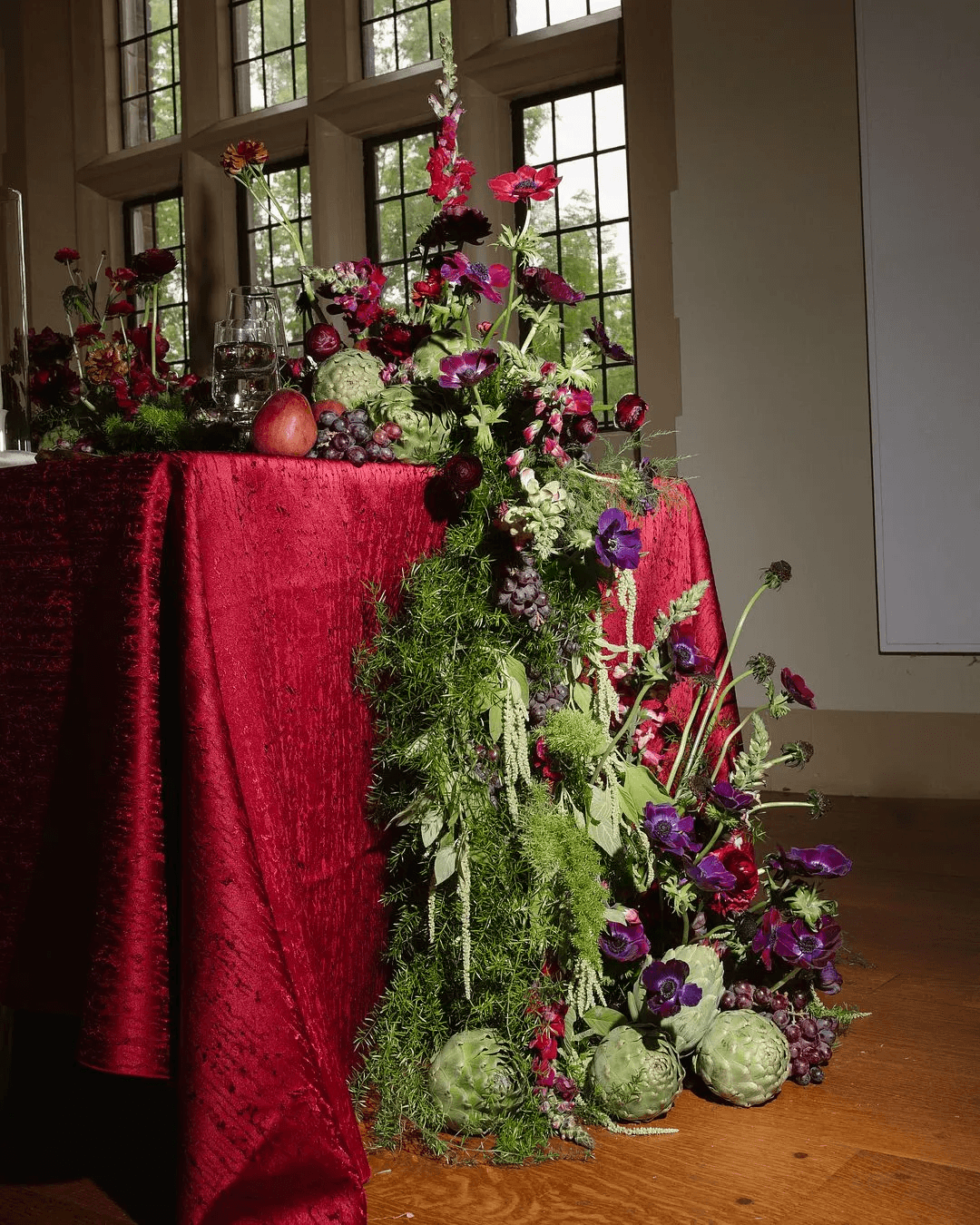 A decorative floral arrangement spills over a table draped in red fabric, creating an elegant atmosphere.