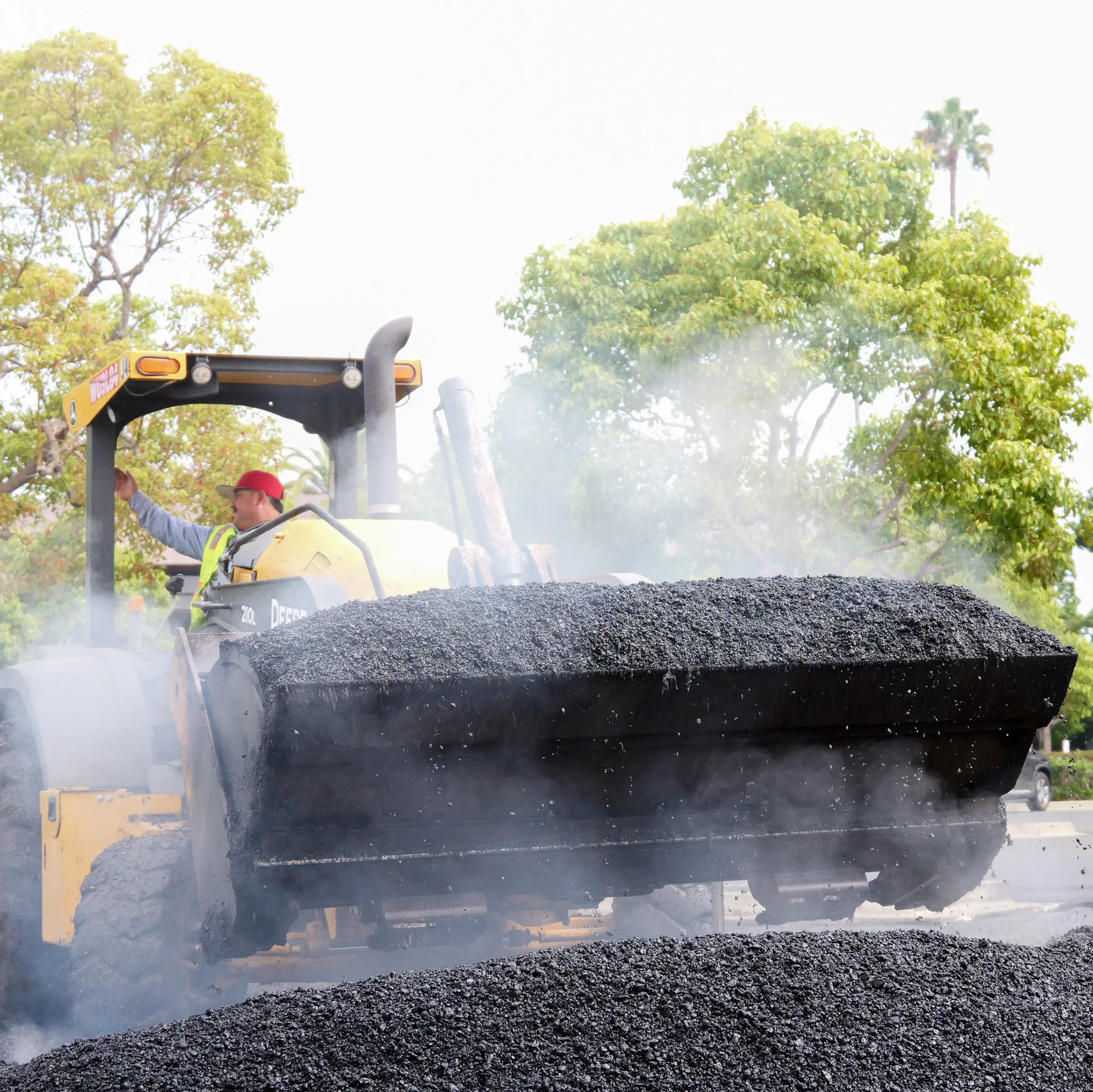 Closeup of steaming hot mix asphalt in scoop