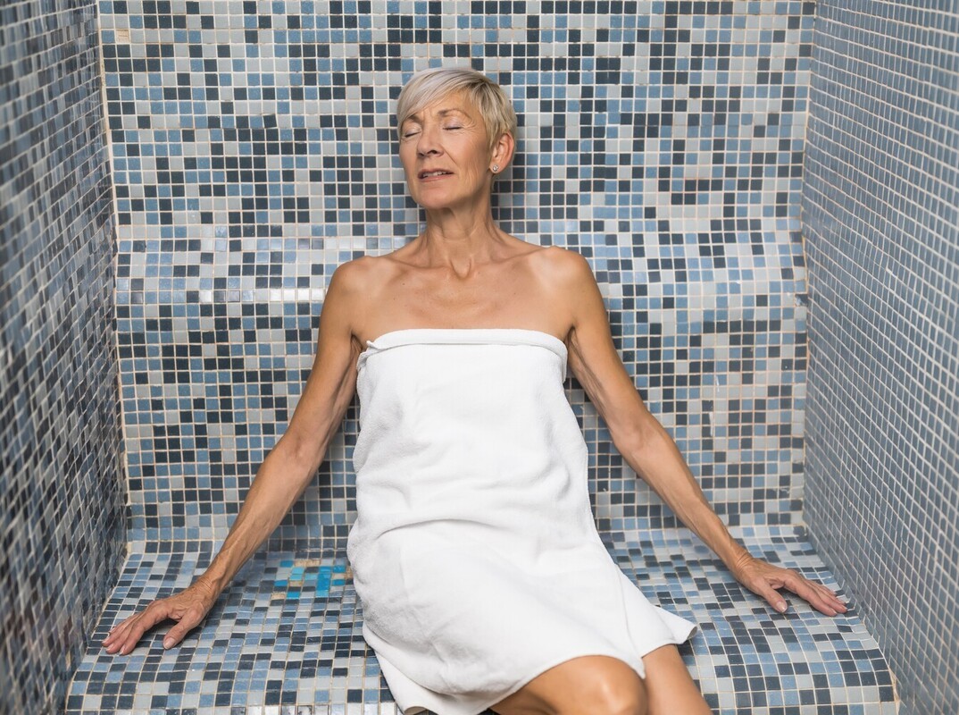 older woman relaxing to enjoy the steam room weight reduction effects after a workout
