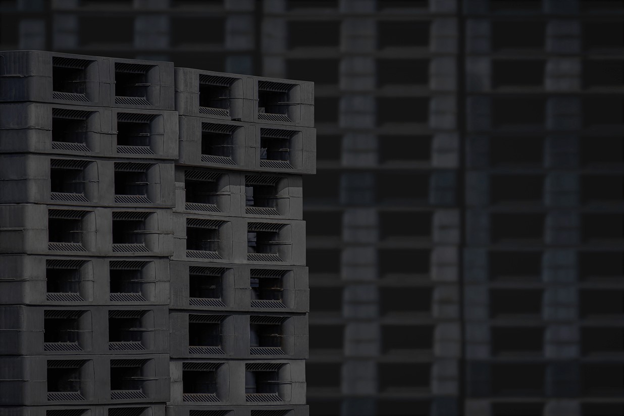 Many black and grey pallets stacked on top of each other