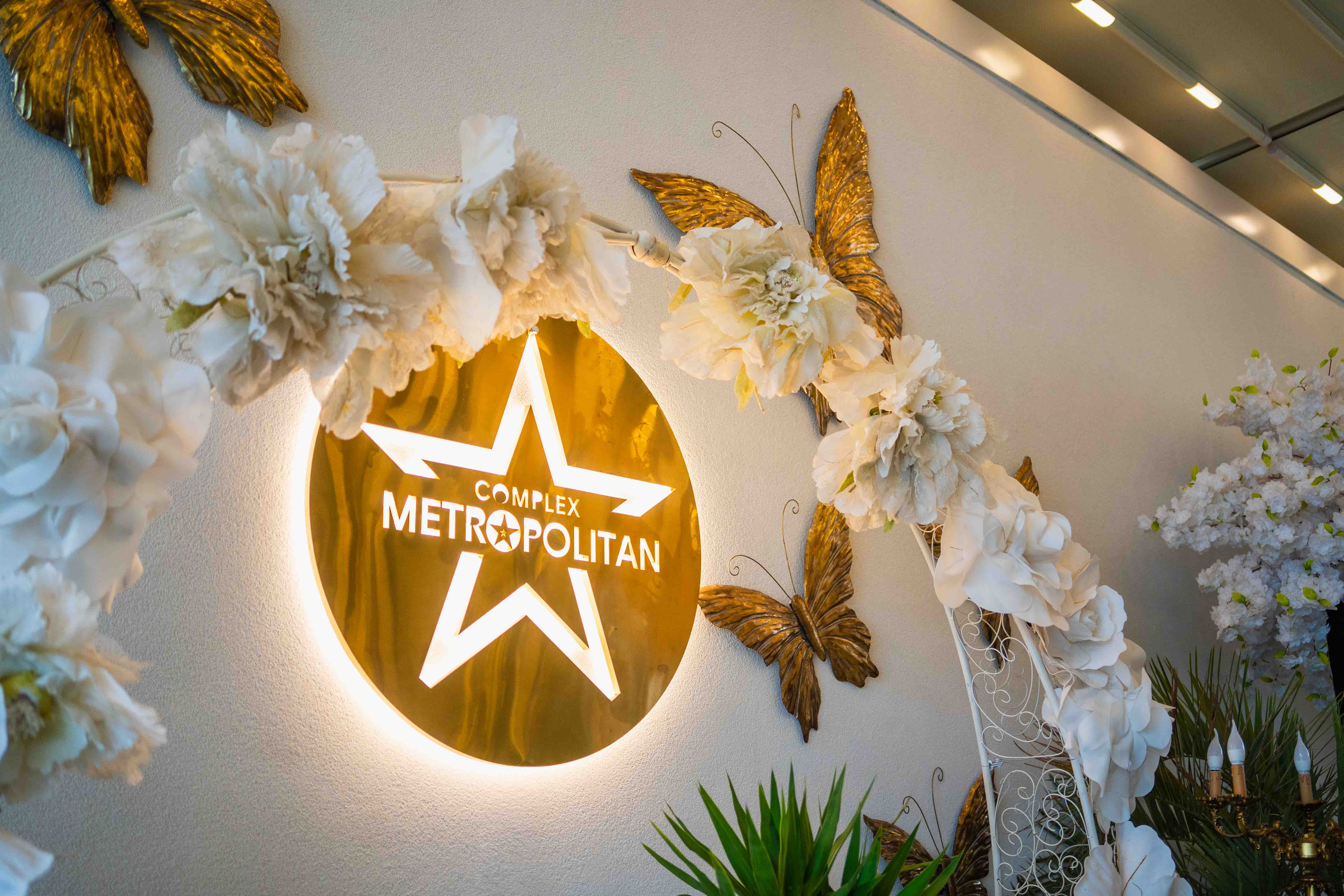 Modern living room with abstract art, beige sectional sofa, indoor plants, and large windows.