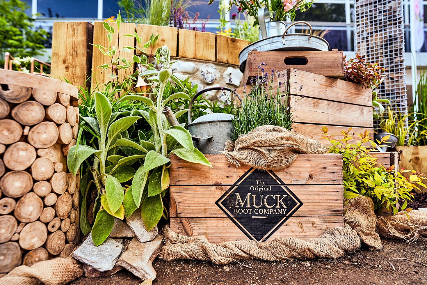 A collection of wooden logs and planks, arranged with greenery in a garden setting.