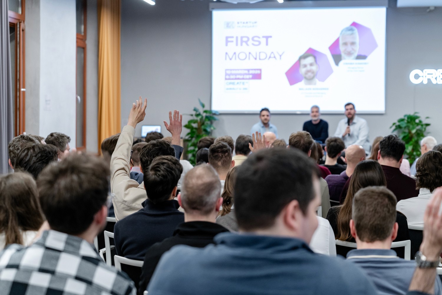 Three people presenting in front of a group with a large screen