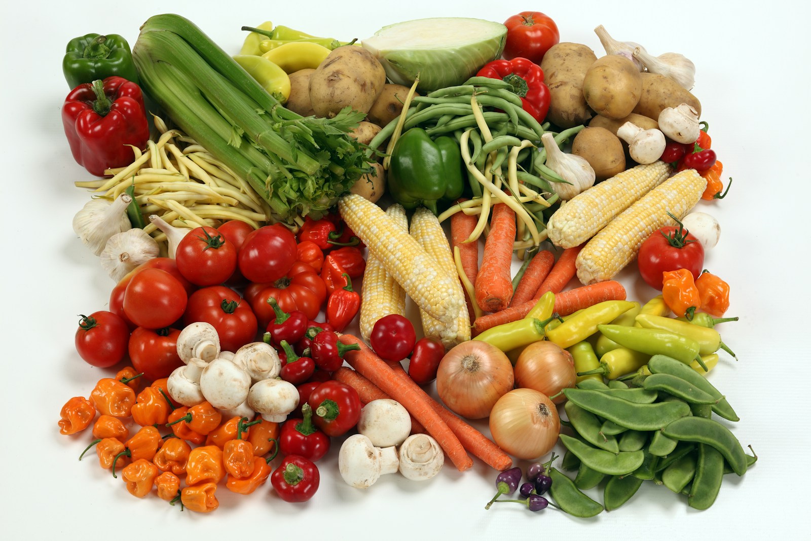 An assortment of colorful fresh vegetables including peppers, corn, carrots, tomatoes and mushrooms, showing the produce that can be part of eating well with IBD