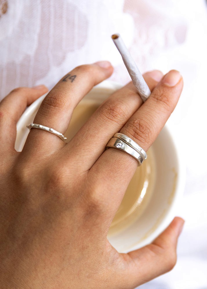 Hand with silver rings holding a cigarette, blurred background