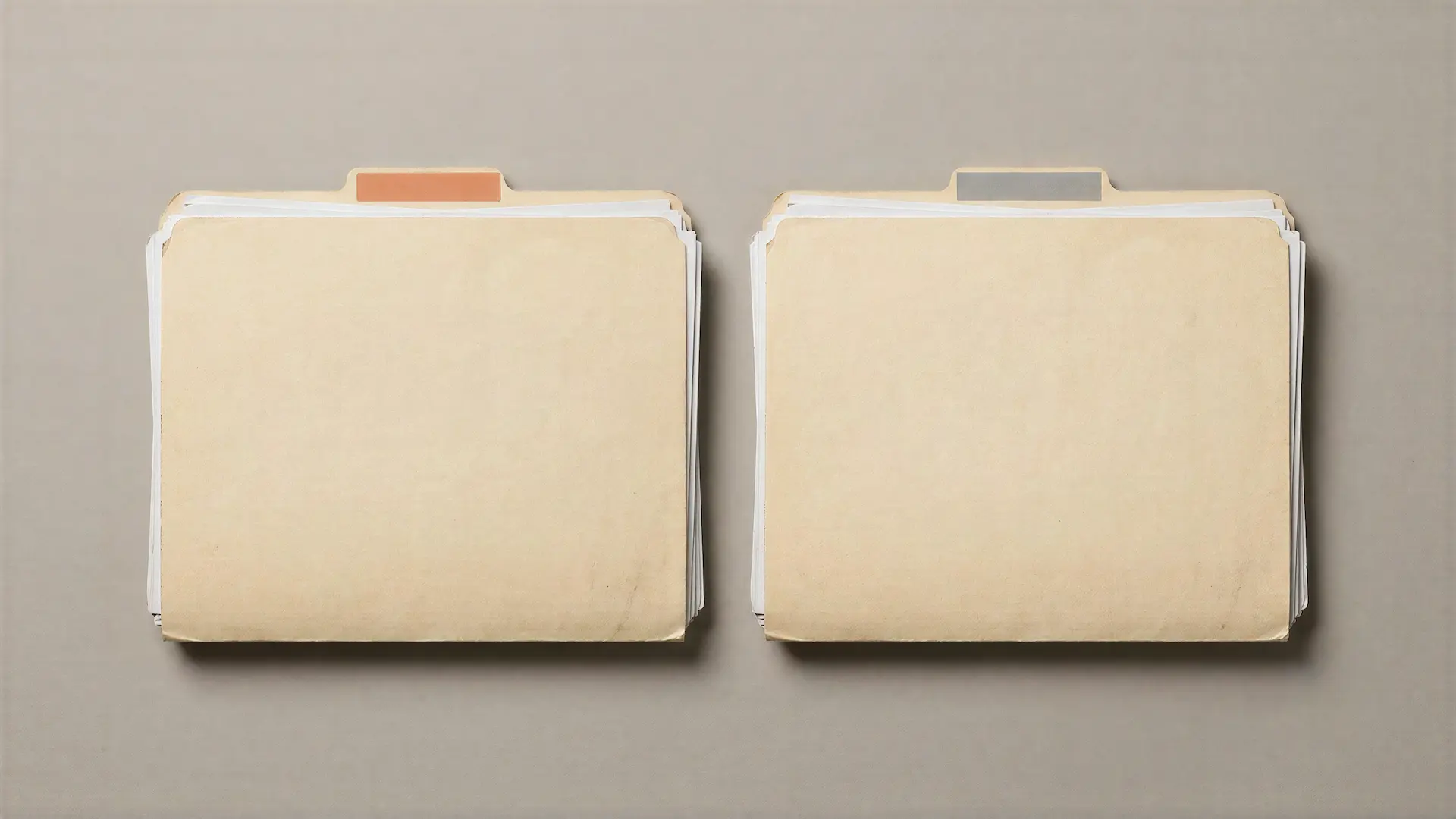 Two identical thick file folders side by side, differing only in one small orange index tab.