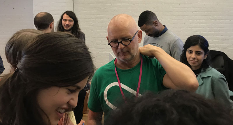 A photo of a group of people standing in a room and talking to each other.