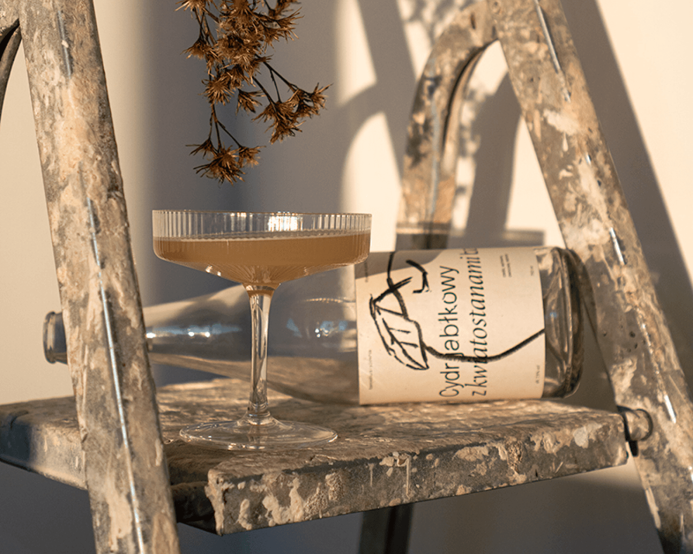 A rustic ladder with decorative items including a glass bowl and a small plant, illuminated by warm light.